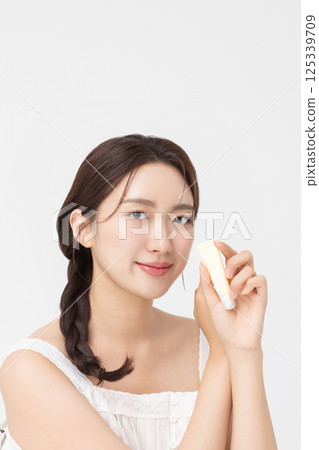 Cropped view of young woman posing with lip balm 125339709