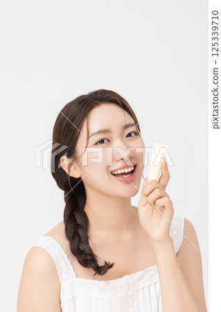 Cropped view of young woman posing with lip balm 125339710