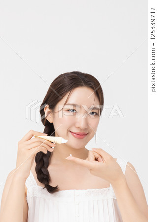 Cropped view of young woman posing with lip balm 125339712