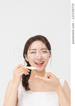 Cropped view of young woman posing with lip balm 125339714