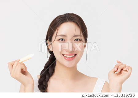 Cropped view of young woman posing with lip balm 125339720