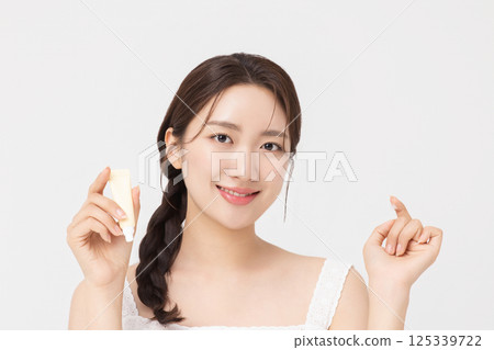 Cropped view of young woman posing with lip balm 125339722