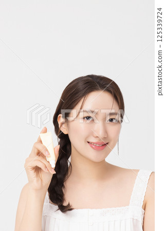 Cropped view of young woman posing with lip balm 125339724