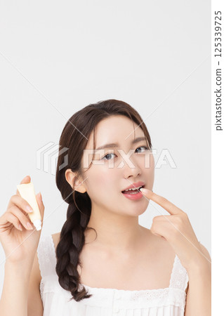 Cropped view of young woman posing with lip balm 125339725