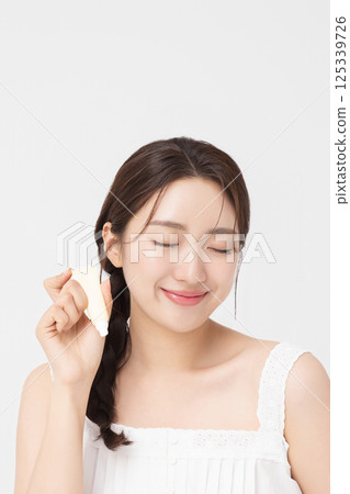 Cropped view of young woman posing with lip balm 125339726