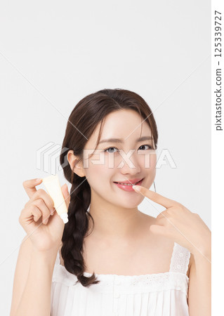 Cropped view of young woman posing with lip balm 125339727