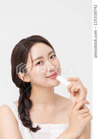 Cropped view of young woman posing with lip balm 125339742