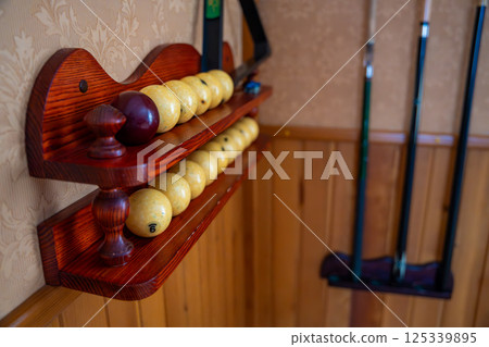 Home billiard setup with white balls, red cue ball, triangle rack, and cues neatly arranged. Concept of indoor recreation and personal hobby space 125339895