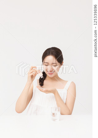 A young woman taking nutritional supplements for her health 125339896