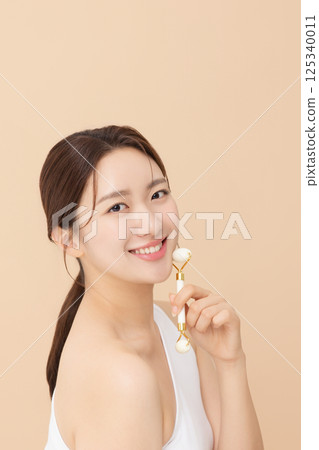 Portrait of a young woman massaging her skin using gua sha 125340011
