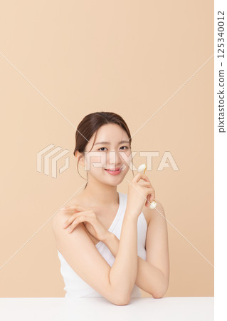Portrait of a young woman massaging her skin using gua sha 125340012