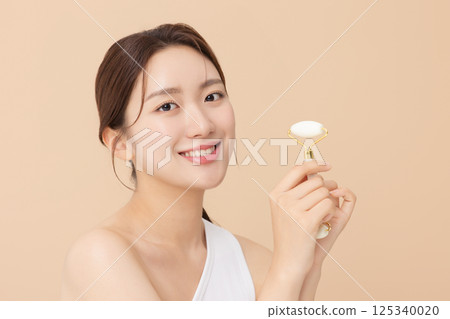 Portrait of a young woman massaging her skin using gua sha Portrait of a young woman massaging her skin using gua sha 125340020