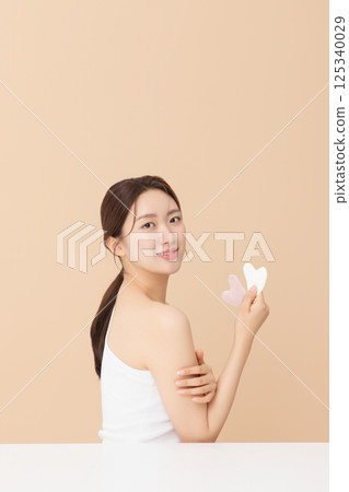 Portrait of a young woman massaging her skin using gua sha 125340029