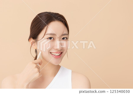 Portrait of a young woman massaging her skin using gua sha Portrait of a young woman massaging her skin using gua sha 125340030