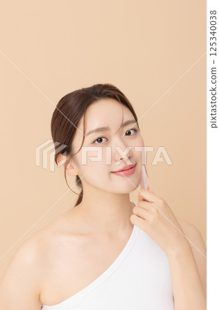 Portrait of a young woman massaging her skin using gua sha 125340038