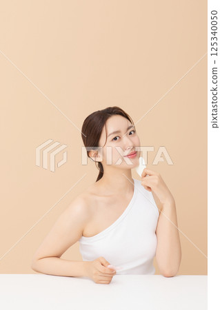 Portrait of a young woman massaging her skin using gua sha 125340050