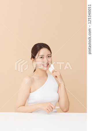 Portrait of a young woman massaging her skin using gua sha 125340051