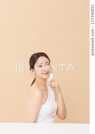 Portrait of a young woman massaging her skin using gua sha 125340052