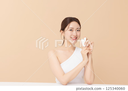 Portrait of a young woman massaging her skin using gua sha Portrait of a young woman massaging her skin using gua sha 125340060