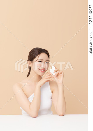 Portrait of a young woman massaging her skin using gua sha 125340072