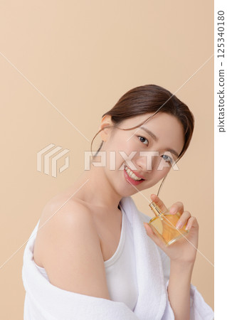 Cropped view of young woman wearing robe and applying oil to skin after shower Cropped view of young woman wearing robe and applying oil to skin after shower 125340180