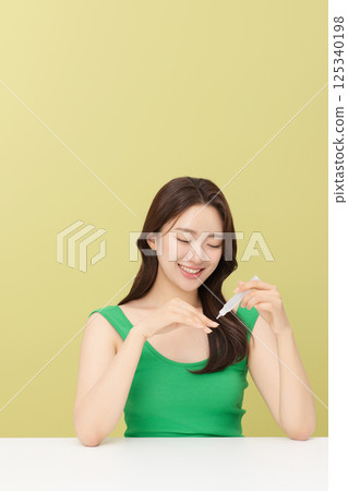 Portrait of young woman taking care of her nails 125340198