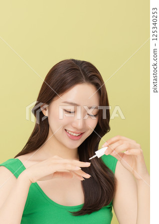 Cropped view of young woman applying nail polish to nails 125340253