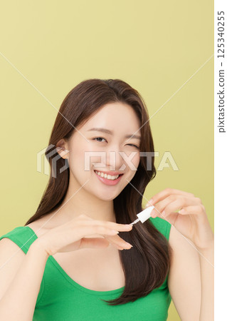 Cropped view of young woman applying nail polish to nails 125340255