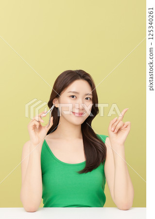Cropped view of young woman taking care of her nails with nail clippers 125340261