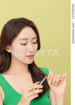 Cropped view of young woman taking care of her nails with nail clippers 125340265