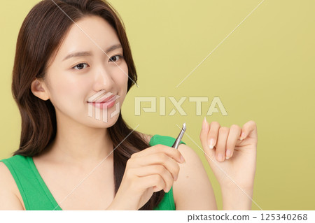 Cropped view of young woman taking care of her nails with nail clippers 125340268