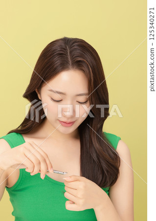 Cropped view of young woman taking care of her nails with nail clippers 125340271
