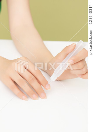 Woman's hands applying nail nourishment 125340314