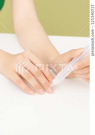 Woman's hands applying nail nourishment 125340315