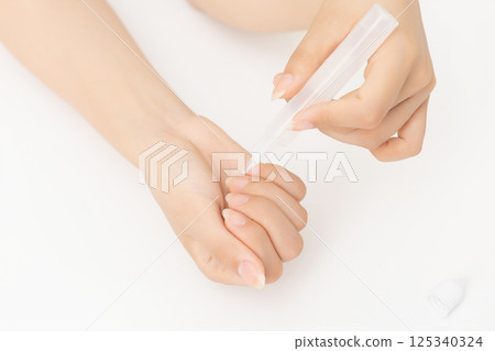 Woman's hands applying nail nourishment 125340324