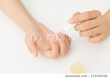 Woman's hands applying nail nourishment 125340346