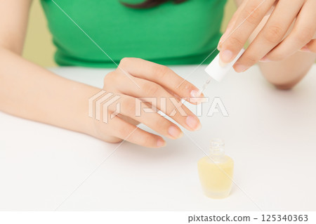 Woman's hands applying nail nourishment 125340363