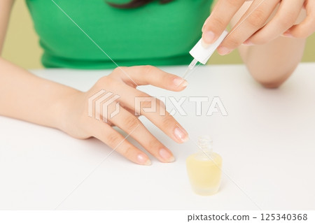 Woman's hands applying nail nourishment 125340368