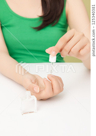 Woman's hands applying nail nourishment 125340381