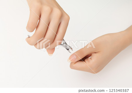 Woman's hands taking care of nail cuticles with nail nippers 125340387