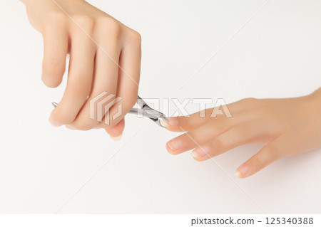 Woman's hands taking care of nail cuticles with nail nippers 125340388