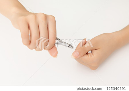Woman's hands taking care of nail cuticles with nail nippers Woman's hands taking care of nail cuticles with nail nippers 125340391