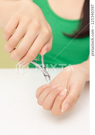 Woman's hands taking care of nail cuticles with nail nippers 125340397