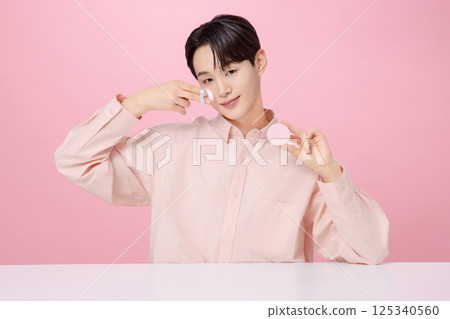 Portrait of a young man posing while holding a cushion Portrait of a young man posing while holding a cushion 125340560