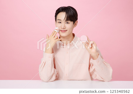Portrait of a young man posing while holding a cushion Portrait of a young man posing while holding a cushion 125340562