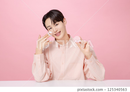 Portrait of a young man posing while holding a cushion Portrait of a young man posing while holding a cushion 125340563