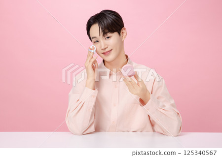 Portrait of a young man posing while holding a cushion 125340567