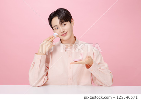 Portrait of a young man posing while holding a cushion 125340571