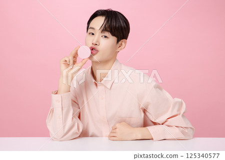 Portrait of a young man posing while holding a cushion Portrait of a young man posing while holding a cushion 125340577