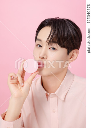 Portrait of a young man posing while holding a cushion 125340578